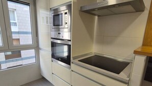 A kitchen with built-in appliances, including a microwave, oven, and stovetop. - 124C Apartamento moderno 2 dormitorios (Gijón)