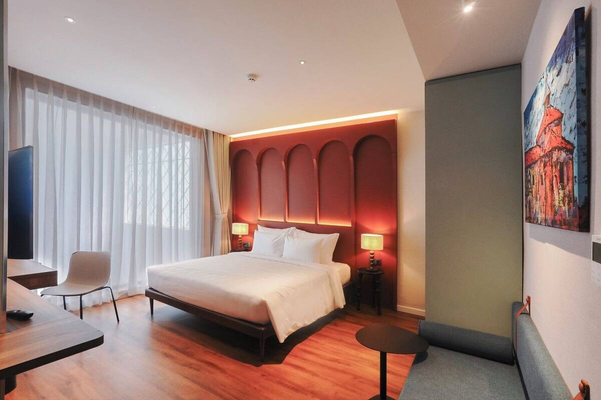Une chambre d’hôtel avec un grand lit, un bureau, une chaise et un tableau au mur.