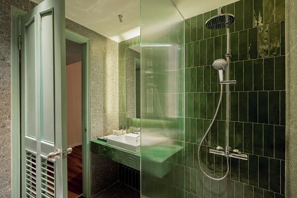 A bathroom with a glass shower enclosure, a sink, and a mirror. - M Village Hotel Đà Nẵng Centre, a brand of Modern Village Lifestyle (Da Nang)
