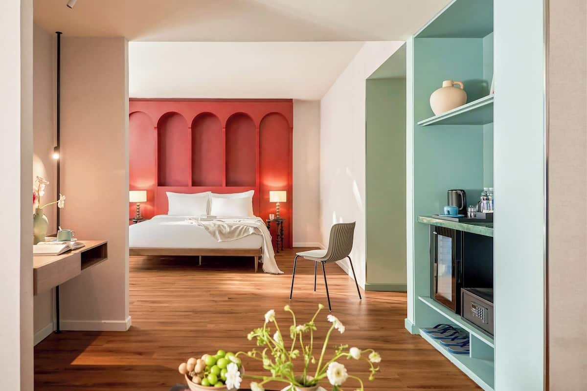 Une chambre d’hôtel moderne avec un grand lit, un bureau avec une lampe et une bibliothèque.
