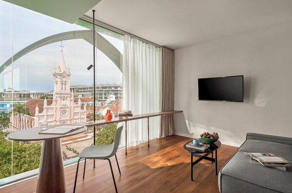 A modern living room with a balcony, a flat-screen TV, a dining table, and a sofa. - M Village Hotel Đà Nẵng Centre, a brand of Modern Village Lifestyle (Da Nang)