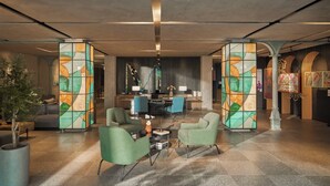 A modern lobby with a reception desk, seating area, and decorative glass panels. - M Village Hotel Đà Nẵng Centre, a brand of Modern Village Lifestyle (Da Nang)