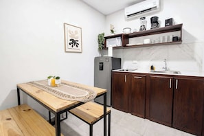 A compact kitchen with a wooden table, dark cabinets, a built-in microwave, and a coffee maker on the countertop.