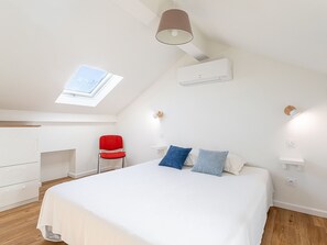 A bedroom with a skylight, a bed with white bedding, a red chair, and a white desk. - Maison Fabrégas by Interhome (La Seyne Sur Mer, Les Sablettes)