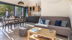 A modern living room with a grey sofa, wooden coffee table, and a dining area with a table and chairs. - Maison Fabrégas by Interhome (La Seyne Sur Mer, Les Sablettes)
