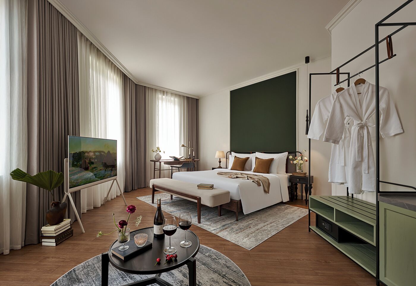 A hotel room with a bed, bedside table, TV, and a robe rack.