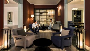 A modern lobby with seating areas, a bar, and a large window with artwork. - Signature by M Village Danang Heritage, a brand of Modern Village Lifestyle (Da Nang)