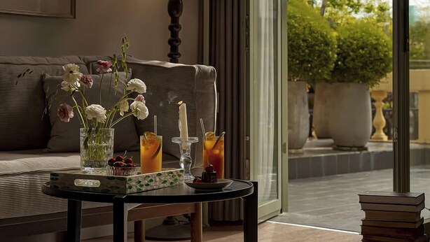 A modern living room with a sofa, a coffee table with drinks and flowers, a lamp, and a view of greenery outside. - Signature by M Village Danang Heritage, a brand of Modern Village Lifestyle (Da Nang)
