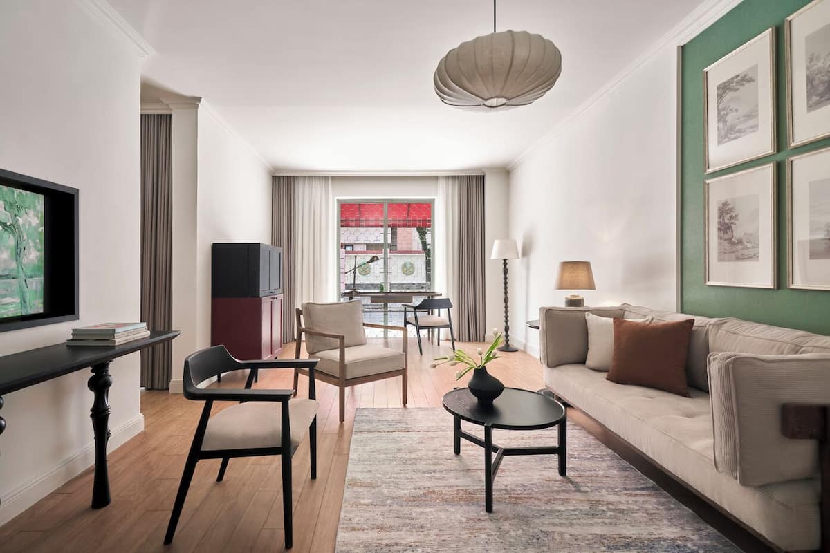 Una sala de estar moderna con un sofá, sillas, una mesa de centro, un televisor y obras de arte en la pared.