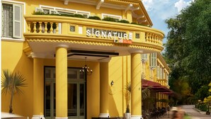 A yellow building with a sign reading "Signature Village." - Signature by M Village Danang Heritage, a brand of Modern Village Lifestyle (Da Nang)