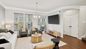 A modern living room with a sofa, armchairs, a coffee table, and a TV mounted on the wall. - 5-Star BWI Hanover 3-Level With Bonus Living Space (Hanover)