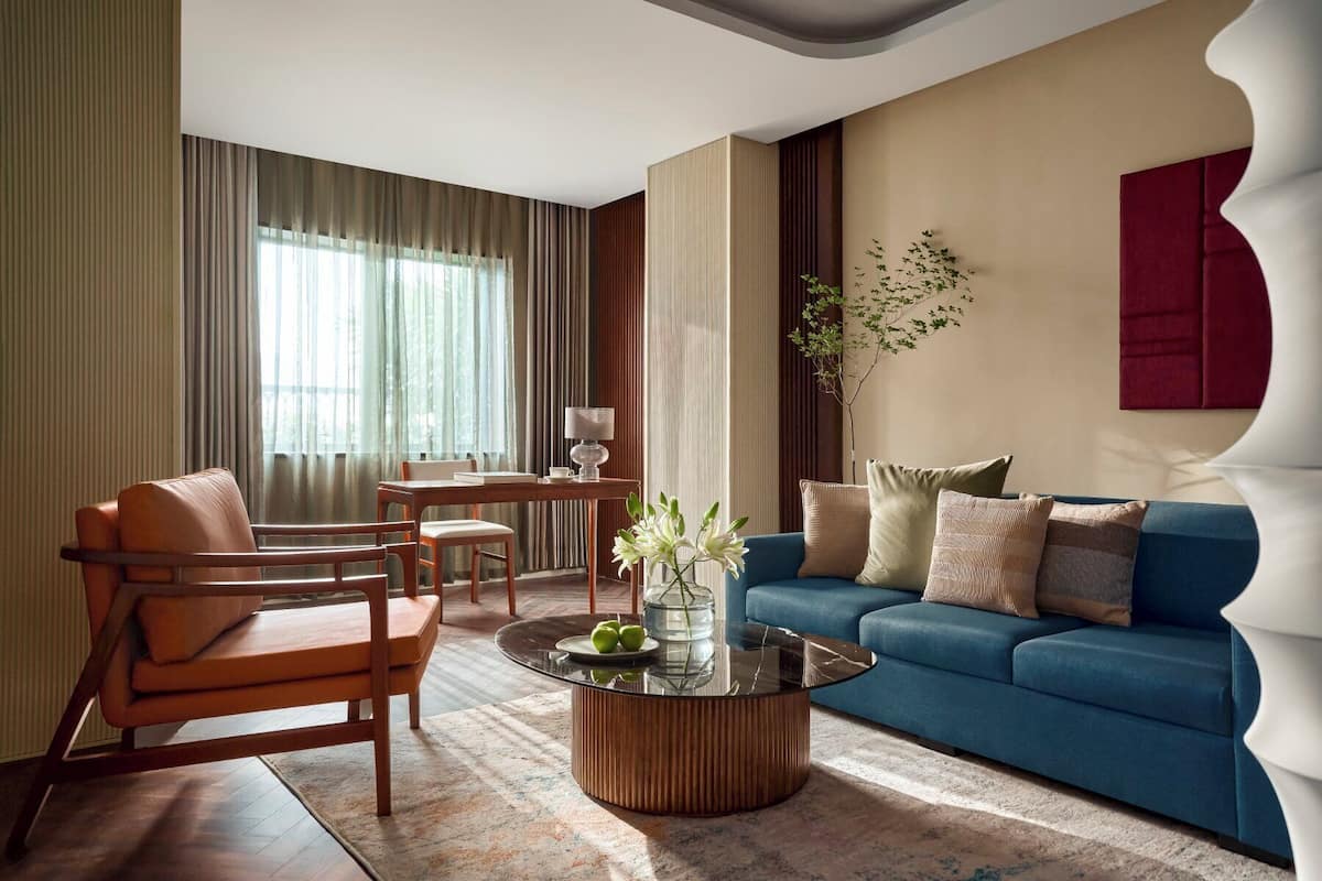Un salon moderne avec un canapé bleu, des chaises en bois, une table basse en verre et un coin repas comprenant une table et des chaises.