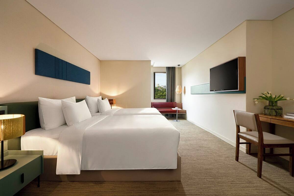 Une chambre d’hôtel avec un grand lit, un bureau, une chaise, une télévision et une vue sur la ville.