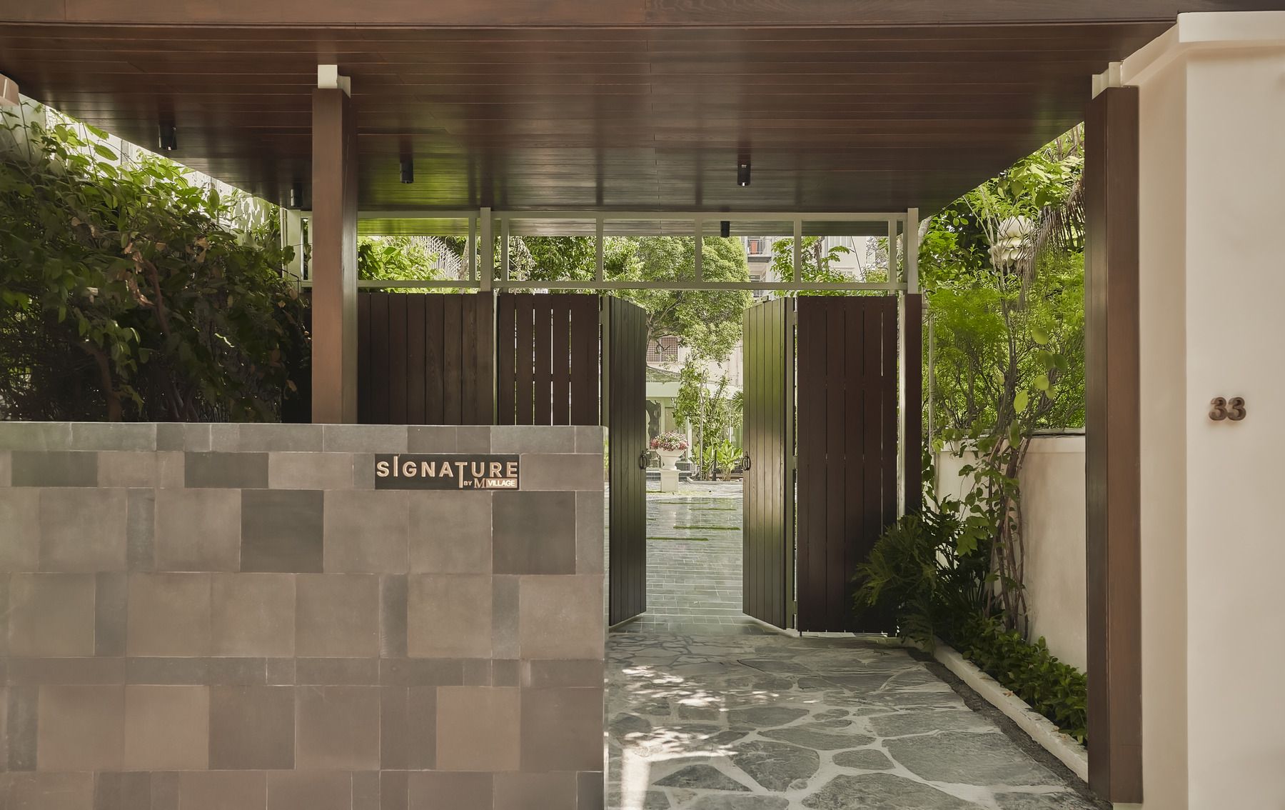 A covered walkway with a stone floor leading to a gated entrance.