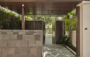 A covered walkway with a stone floor leading to a gated entrance. - President Maison Signature by M Village, a brand of Modern Village Lifestyle (Ho Chi Minh City)