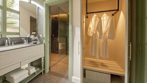 A modern bathroom with a vanity, a large mirror, and a walk-in closet with hanging robes. - President Maison Signature by M Village, a brand of Modern Village Lifestyle (Ho Chi Minh City)