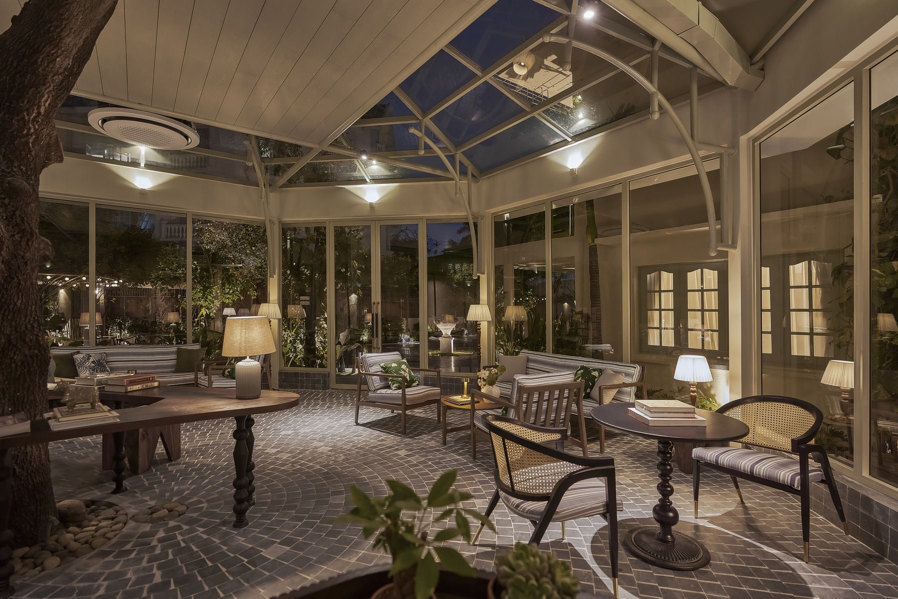 A conservatory with a glass ceiling, furnished seating, and a tiled floor.