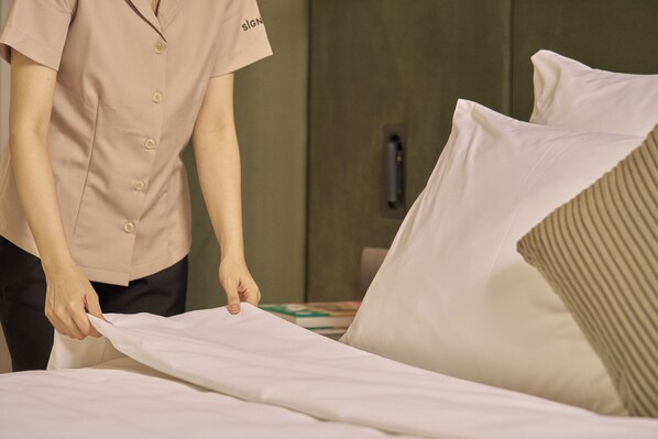 A person adjusting a bedspread in a hotel room. - President Maison Signature by M Village, a brand of Modern Village Lifestyle (Ho Chi Minh City)