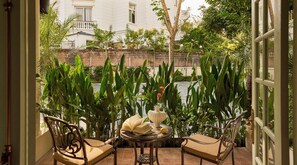 A balcony with a table, chairs, and a view of a building and greenery. - President Maison Signature by M Village, a brand of Modern Village Lifestyle (Ho Chi Minh City)