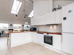 A modern kitchen with white cabinetry, a wooden countertop, and built-in appliances.