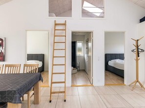 A modern interior with a dining area, a loft bedroom, and a bathroom.