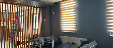 Une chambre moderne avec un canapé, une table et une fenêtre équipée de stores.