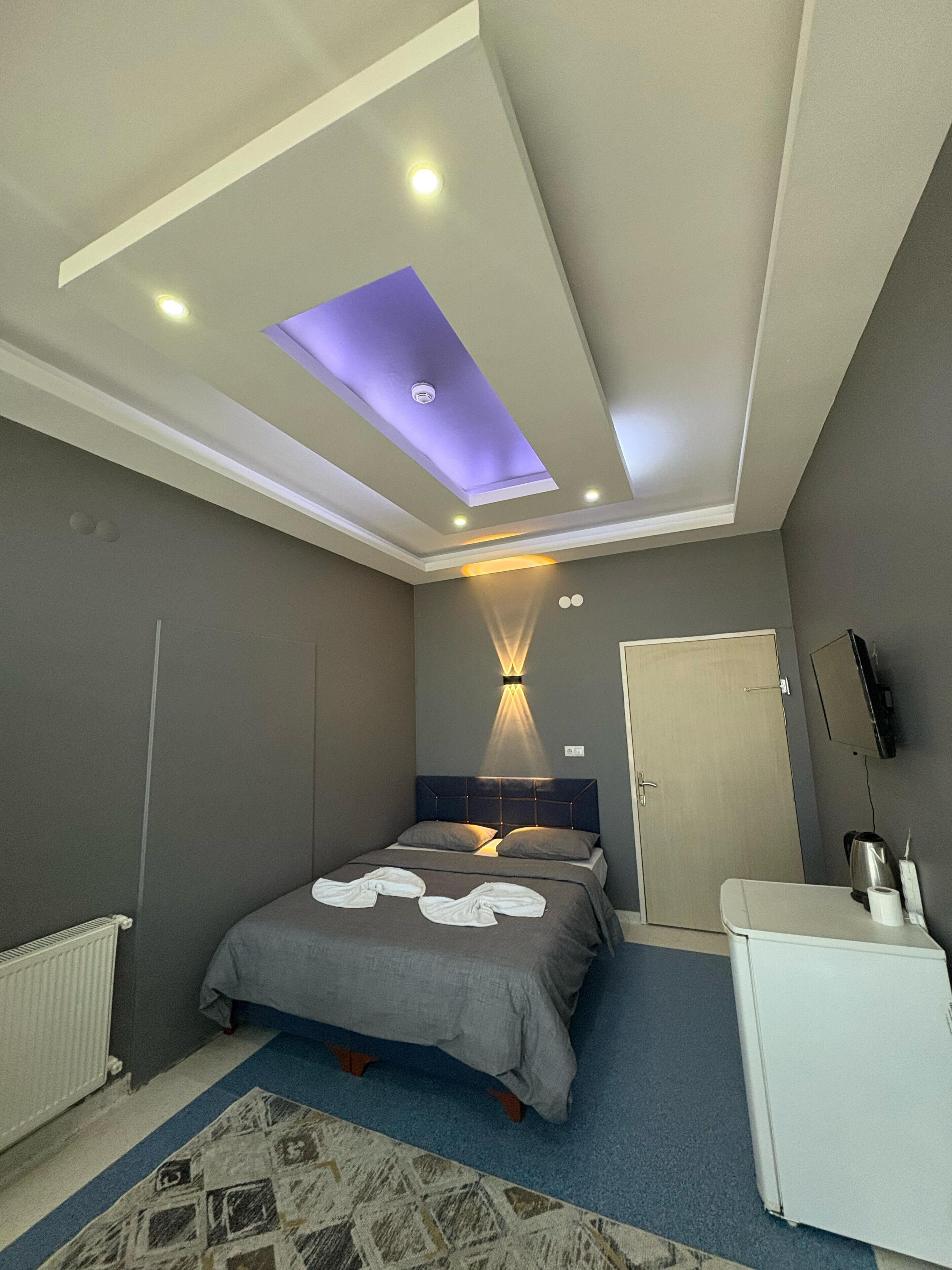 A modern bedroom with a bed, a desk, and a ceiling light fixture.
