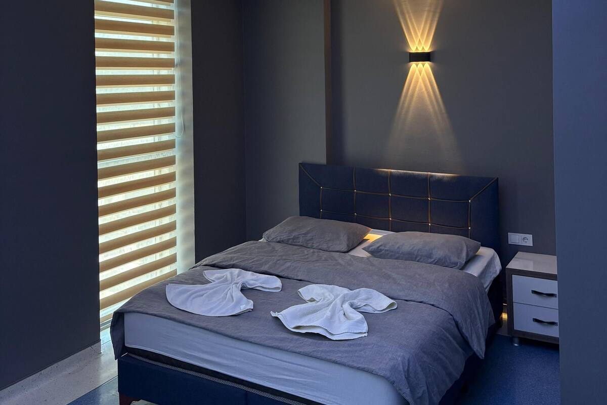 A modern bedroom with a skylight, a bed with a headboard, and a bedside table.