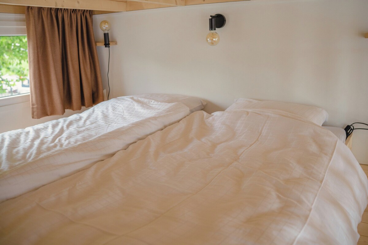 Une chambre à coucher avec un lit, une fenêtre avec des rideaux et deux appliques murales.