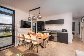 A modern kitchen with a dining area, large windows, and a view of the outdoors. - House With Three Bathrooms, on a Holiday Park (Loosdrecht)
