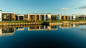 Un moderno complejo residencial con varias casas a lo largo de un canal, con grandes ventanales y arquitectura contemporánea.