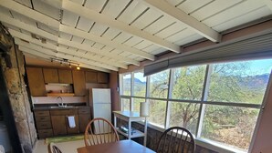 Un comedor con mesa y sillas de madera, una cocina con armarios de madera y un ventanal con vistas al exterior.