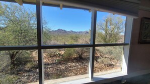 Una ventana con vistas a un paisaje desértico, incluyendo montañas y vegetación escasa.