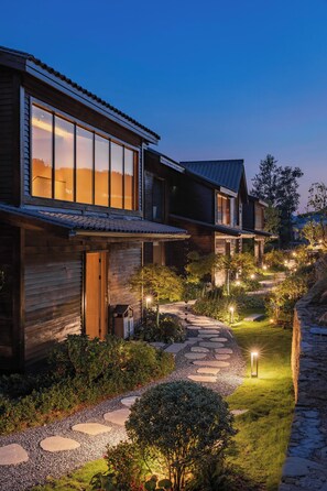 A modern house with a stone pathway leading to the entrance, surrounded by lush greenery and illuminated by ambient lighting. - Zhangjiajie Manxin Joint Store (Zhangjiajie)