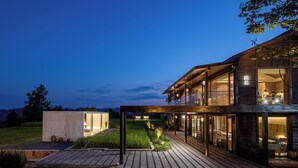 Un edificio moderno con fachada de vidrio, terraza de madera y un interior bien iluminado.