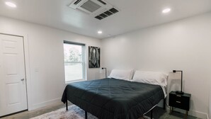 A bedroom with a bed, a nightstand, a lamp, a window, and a door. - Riverbend Ranch Cabin #1 (Normandy)