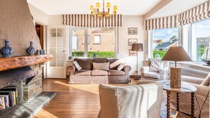 A cozy living room with a fireplace, comfortable seating, and large windows offering a view of the outside. - Villa Near Belgian Coast With Sea Views (Koksijde)