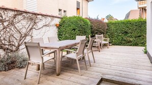An outdoor patio with a wooden table and chairs, surrounded by greenery and a white brick wall. - Villa Near Belgian Coast With Sea Views (Koksijde)