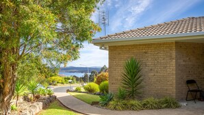 A brick house with a tiled roof, a paved driveway, and a well-maintained lawn. - Sapphire Belle: Views and boat Parking (Eden)
