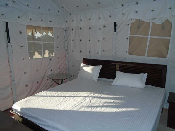A bedroom with a large bed, a small table, and a window with a view. - Pine pioneer the eco resort  (Kosiyakutoli)