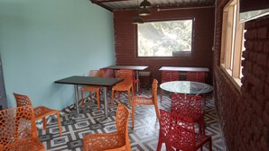 Una cafetería con sillas y mesas anaranjadas y rojas, y un suelo estampado.