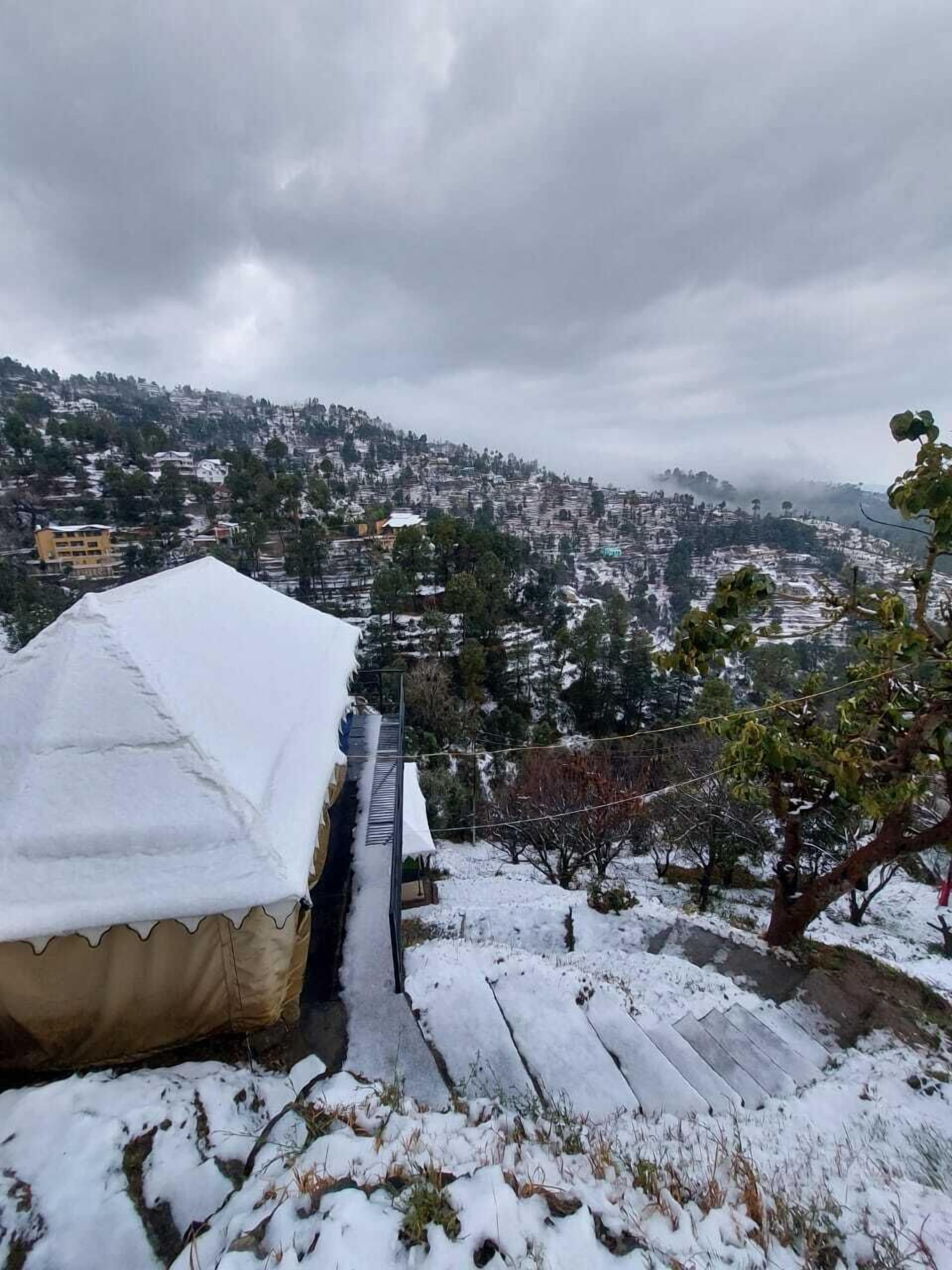 A snow-covered outdoor area with a building and a view of a hilly town.