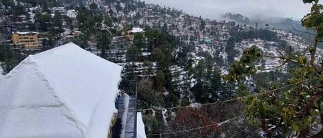 A snow-covered outdoor area with a building and a view of a hilly town.