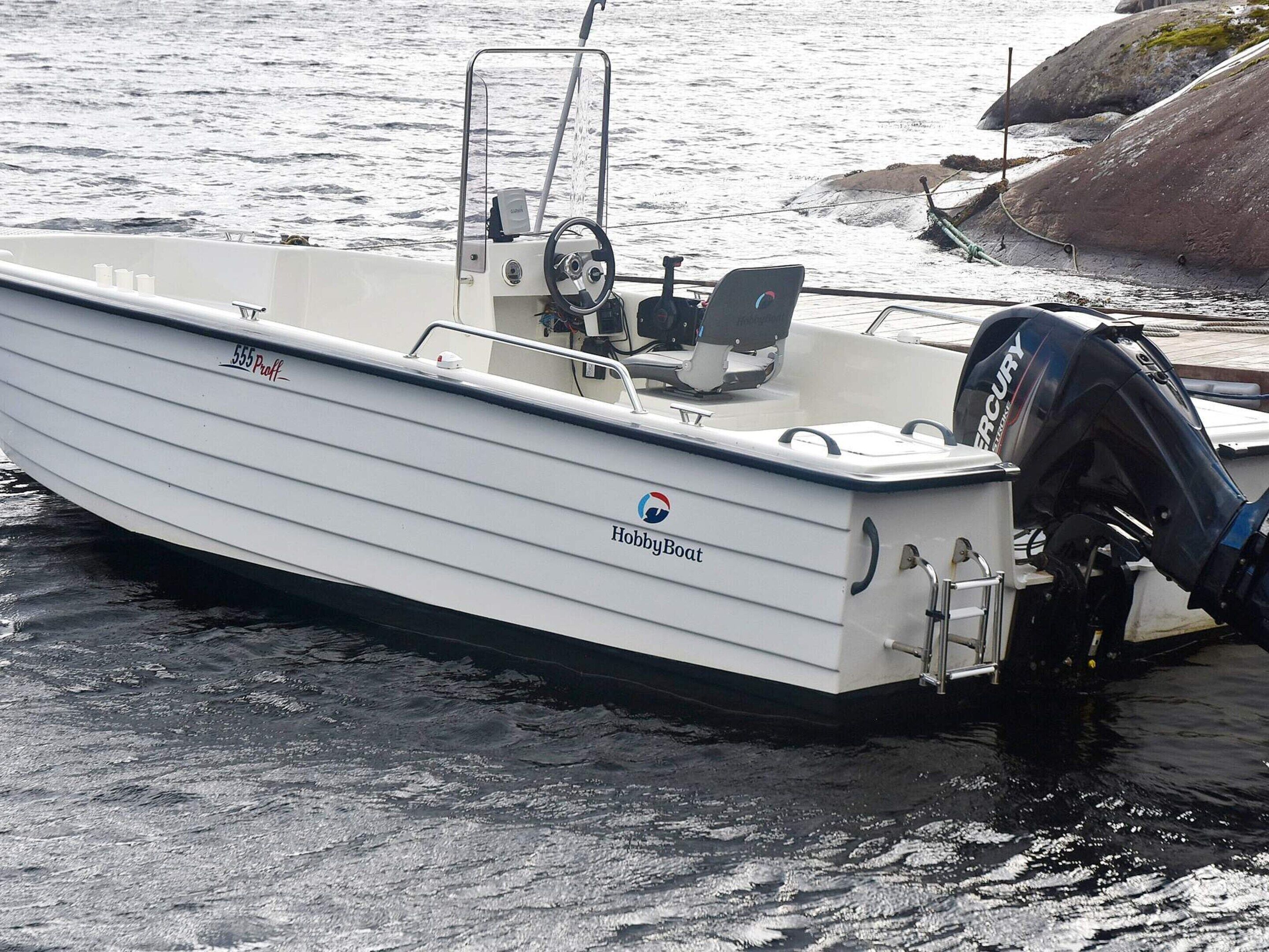 A white motorboat named "555 Proff" docked at a marina with a Mercury outboard motor.