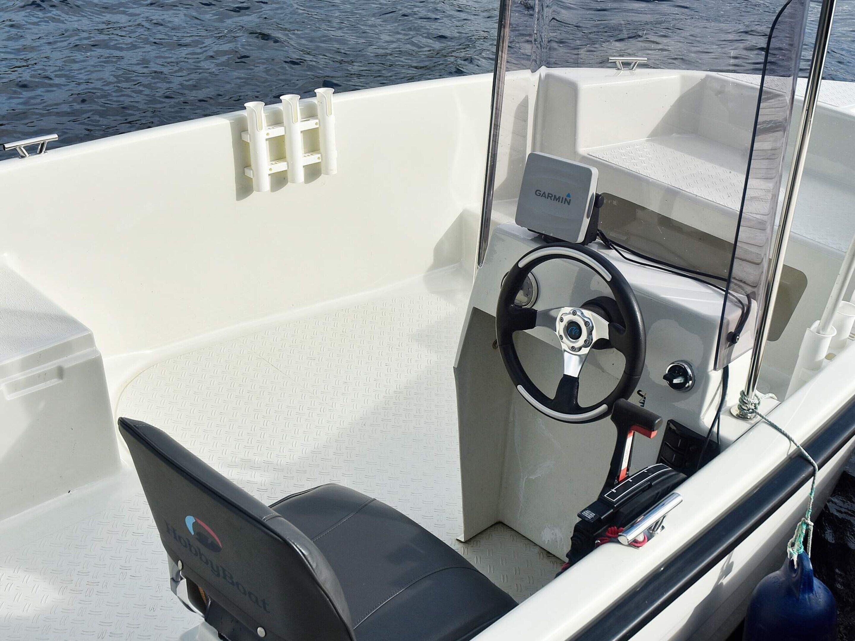 A boat's interior with a steering wheel, a Garmin device, and a seating area.