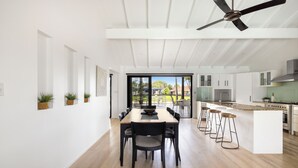 Een moderne keuken met een centraal eiland, barstoelen en een plafondventilator.