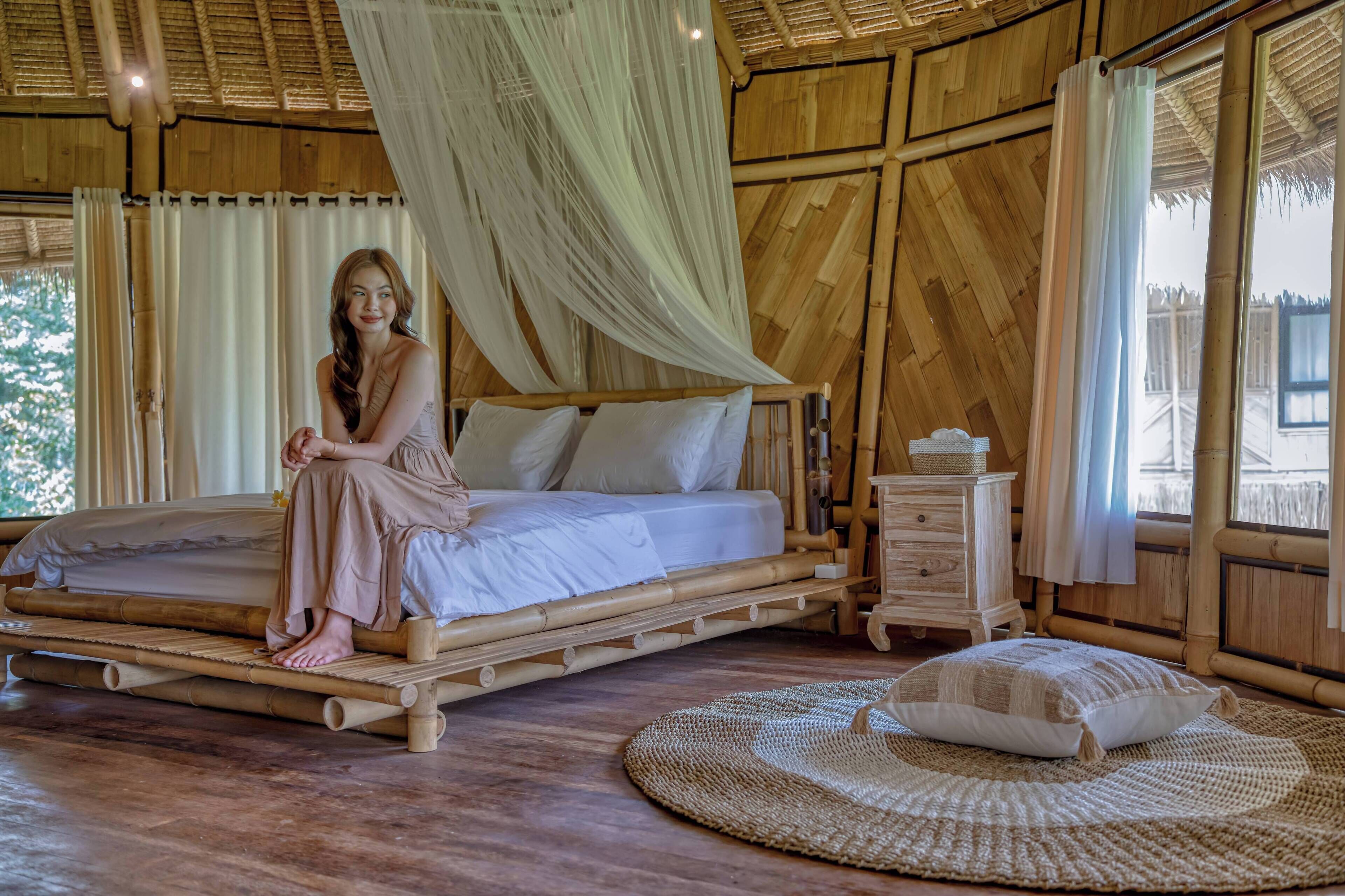 A room with a bed, a bedside table, and a woven mat on the floor.