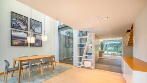 A modern interior with a wooden dining table, chairs, and a built-in bookshelf. - GuestReady - Paradisiac Villa in Tróia (Praia de Troia)