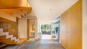 A modern interior with a staircase, a bathroom, and a view of the outdoors. - GuestReady - Paradisiac Villa in Tróia (Praia de Troia)