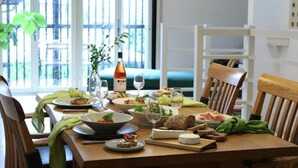 A dining table set with various dishes, glasses, and a bottle of wine, with a view of a balcony in the background. - Kamakura Vacation House (Kamakura)